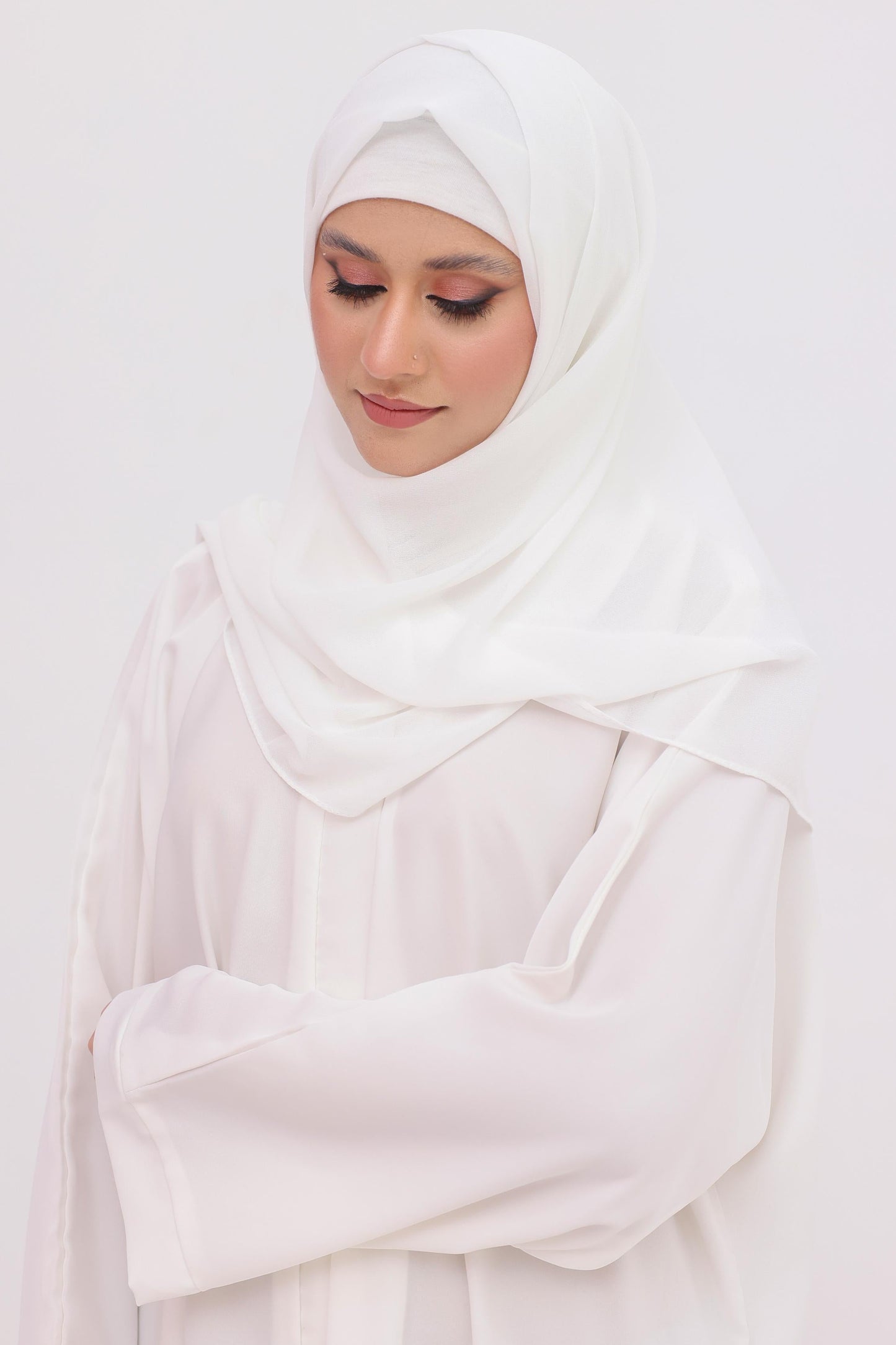 Woman wearing a white hijab , cap and white abaya