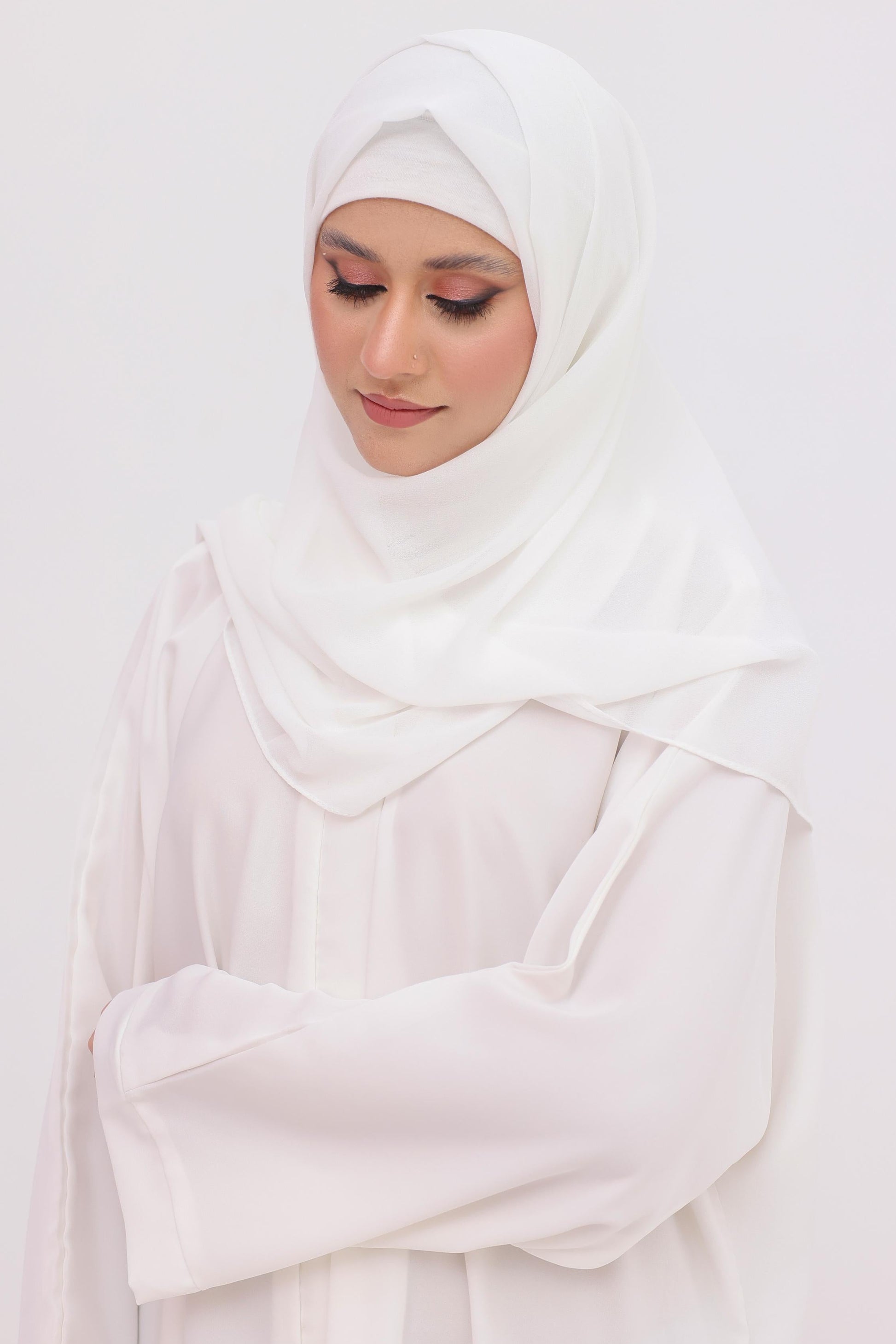 Woman wearing a white hijab , cap and white abaya