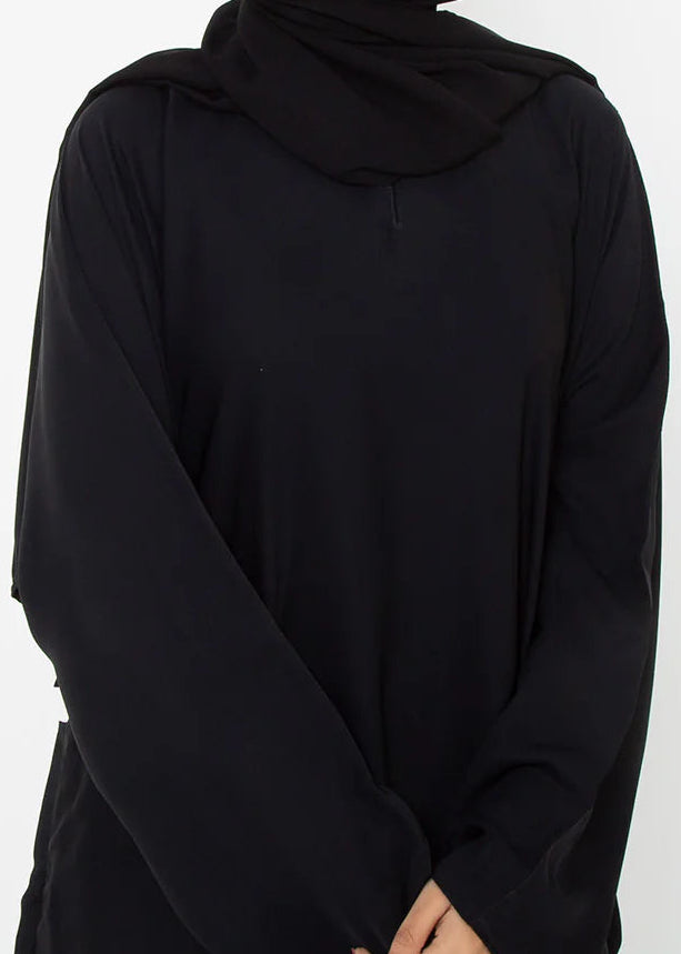 Woman wearing a black abaya and hijab on a white background