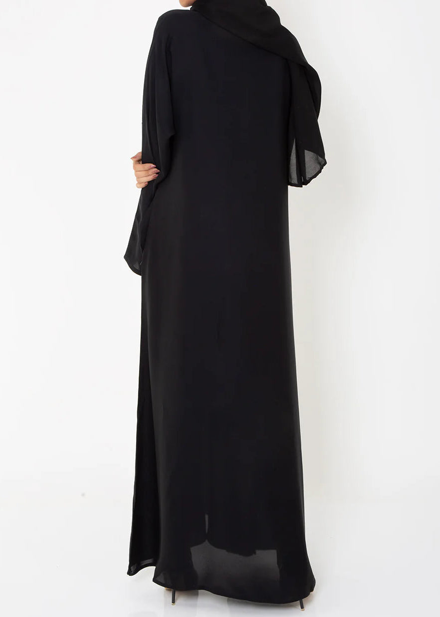 Woman wearing a black abaya and hijab on a white background