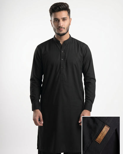 Man wearing a black kurta with a close-up of the brand label on a white background